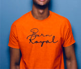 Clear close-up of orange, round neck t-shirt on African American Male posing on slate blue background.  Printed t-shirt has "Born Royal" in cursive graphic, centered horizontally across chest.  2 lines--Born on first line, Royal on second.  T-shirt 100% cotton.