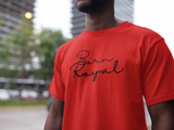 Clear image of red, round neck t-shirt on African American Male standing in front of blurred background scenery of building skyscraper and trees. Printed t-shirt has "Born Royal" in cursive graphic, centered horizontally across chest. 2 lines--Born on first line, Royal on second. T-shirt 100% cotton.